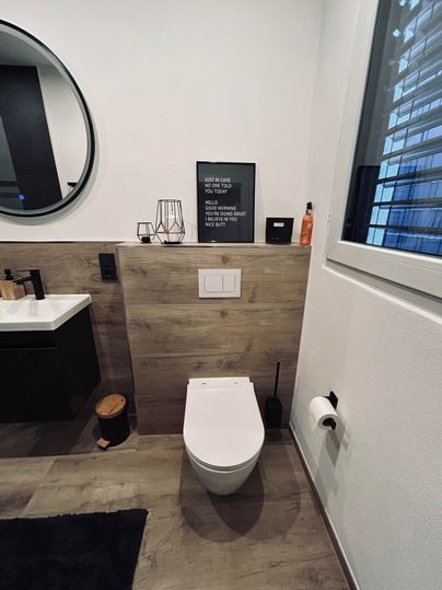 A modern bathroom with a wall-mounted toilet and a large mirror.