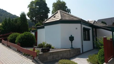 Een modern, wit huis met een puntdak. Op de voorgrond zijn goed onderhouden planten en een pad van stenen te zien.