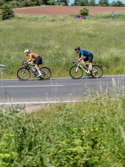 Two cyclists on a country road in a rural setting.