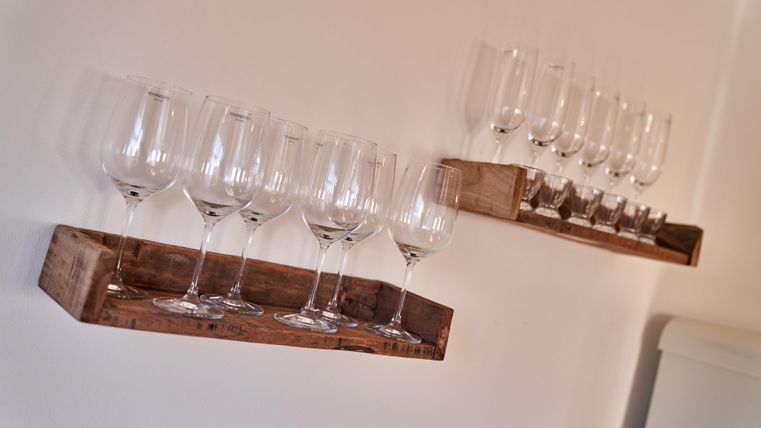 Zwei Regale aus Holz mit Gläsern stehen an der Wand. Die Gläser sind aufrecht und ordentlich angeordnet.