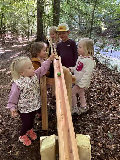 Kinder spielen im Wald an der Waldkugelbahn.
