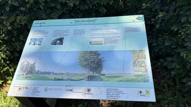 Een informatiebord over de regio "Heckenland". Het toont een beschrijving van het landschap met tekst en afbeeldingen.