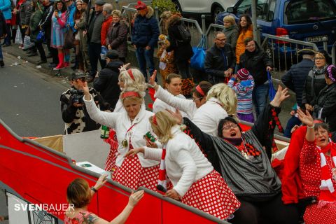 A joyful carnival celebration with people in colorful costumes. The participants on a float are dancing and having fun.