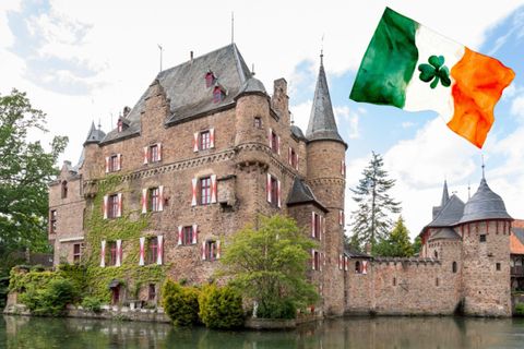 Un château pittoresque avec des tours et un parc environnant. Au premier plan, un drapeau irlandais flotte.