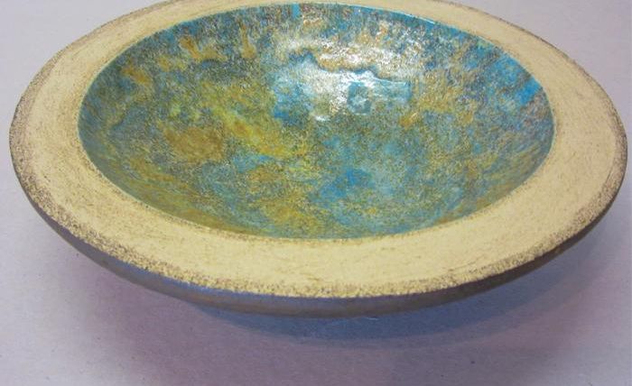 An artistic bowl with a blue and gold interior. The rim is kept in light beige.