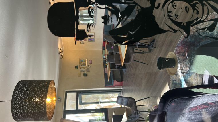 Un café élégant avec des meubles modernes et une grande vitrine. Sur le mur, on peut voir la silhouette intéressante d'une personne avec un chapeau haut de forme et des jumelles.