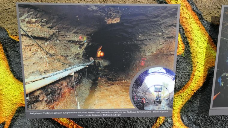 Ein dunkler Tunnel mit sichtbaren Rohren an der linken Seite. Neben dem Tunnel ist ein kleines, rundes Bild, das eine andere Perspektive zeigt.