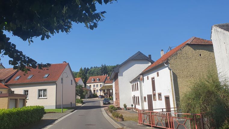 Straat in een dorp met huizen en blauwe lucht.