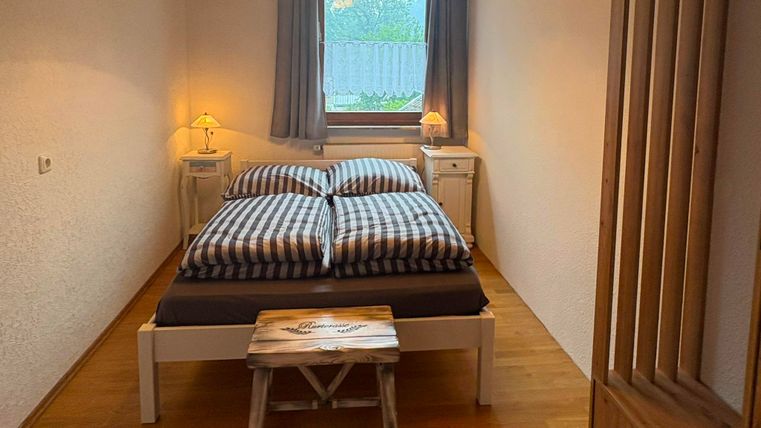 A cozy bedroom with a double bed and checkered bedspreads. The warm wood tones and windows create an inviting atmosphere.