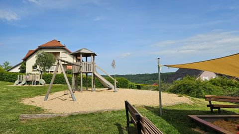 Terrain de jeu en sable avec des tours de jeu en bois pour enfants et une grande aire de sable avec un auvent.