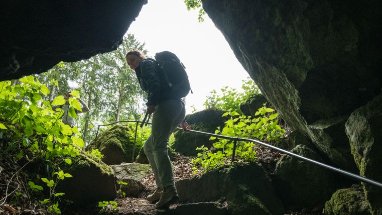 Une femme à la sortie d'une grotte sombre monte les marches vers la lumière et regarde en arrière dans la grotte.