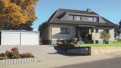 A modern single-family house with a well-maintained front garden. On the left is a garage and in the background, the autumn tree glows.