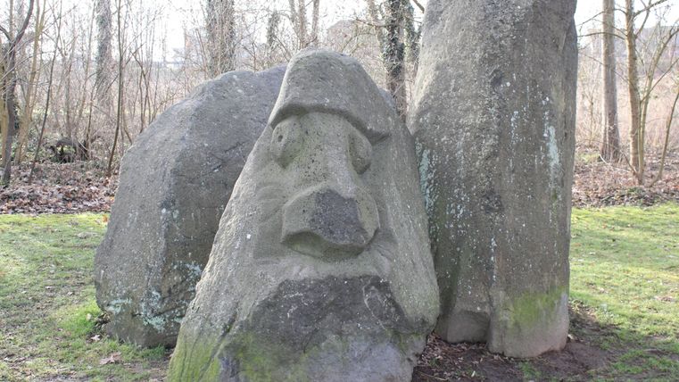 Three large stones standing side by side, one of which has a carved face