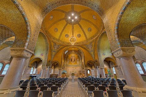 Eine prächtige Kirche mit goldenen Kuppeln und kunstvollen Verzierungen. Die Sitzreihen sind ordentlich angeordnet, bereit für die Besucher.