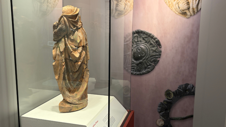 In einer Vitrine steht ein Statuenfragment aus Terrakotta.
