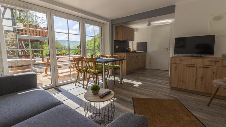 Un appartement moderne avec un coin salon confortable et beaucoup de lumière naturelle. La cuisine est lumineuse et accueillante, donnant sur la terrasse.