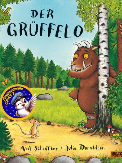 Grüffelo bevindt zich met een kleine muis in een bos, hij houdt zich aan een boom vast en glimlacht, op de poster staat "De Grüffelo - Puppentheaterspatz - Axel Scheffler - Julia Donaldson"