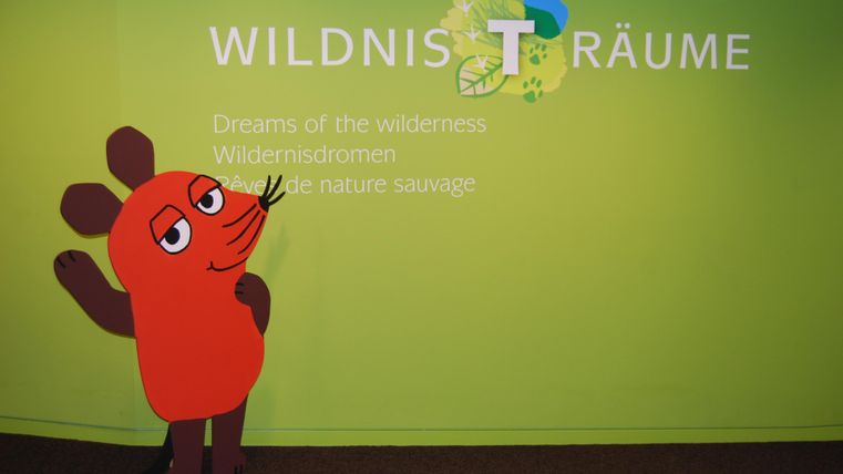 The image shows the mouse from Die Sendung mit der Maus in front of the Wildnis-Träume inscription.