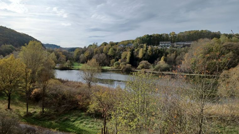 Paysage avec bassin de rétention, entouré d'arbres et de collines.