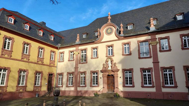 Binnenplaats van het klooster van Steinfeld met barokke gevel en klok.