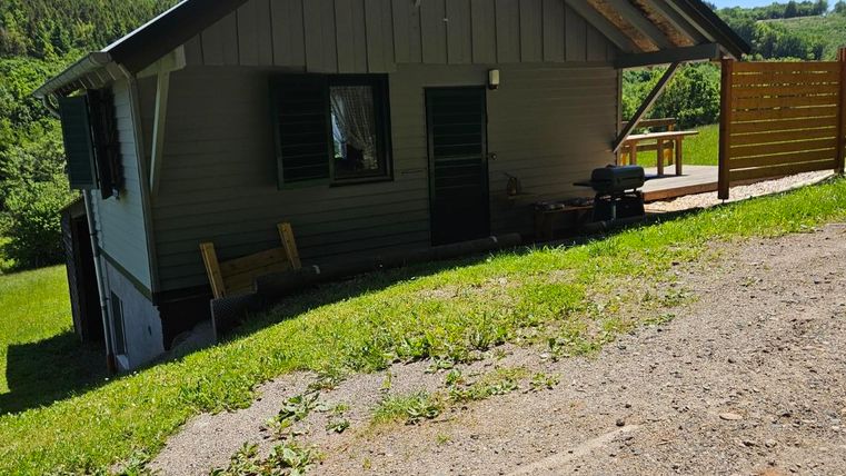 A small house on a hill surrounded by green grass. The sky is clear and blue, ideal for a quiet break.