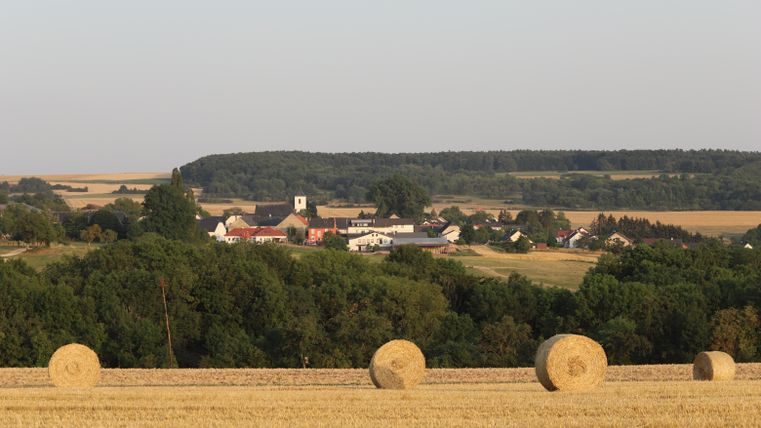 Landscape with straw bales and village in the background.