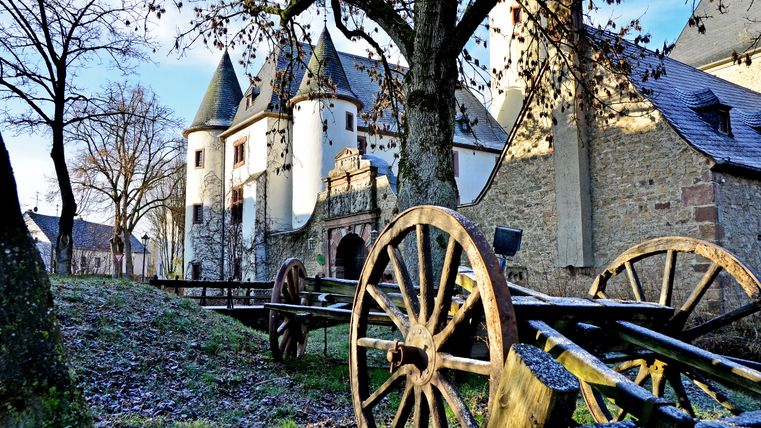 Château de Rittersdorf en hiver avec de vieilles roues de wagons en bois au premier plan.