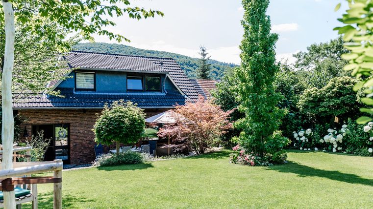 Een mooi huis omringd door een goed onderhouden tuin. Het landschap is groen met bomen en bloeiende planten.