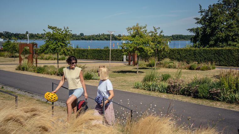 Deux personnes se promènent dans le Seepark Zülpich le long d'un chemin avec vue sur le lac.