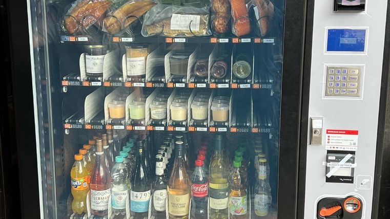 Ein Verkaufsautomat mit einer Vielzahl von Snacks und Getränken. Die Auswahl umfasst Sandwiches, Süßigkeiten, Softdrinks und alkoholische Getränke.