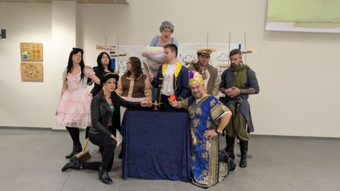 A group of people in various costumes is posing around a table. They appear joyful and are celebrating a special occasion.