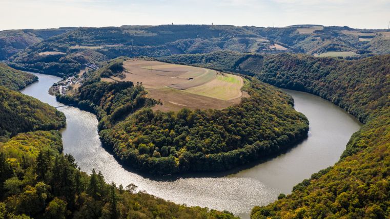 Luchtfoto van een rivierbocht in een bebost landschap met velden.