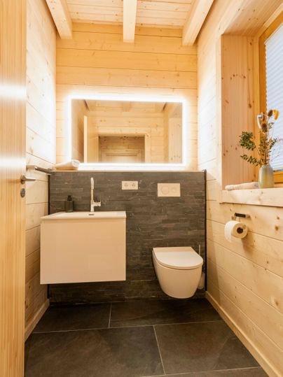 Ein modernes Badezimmer mit Holzverkleidung und eleganten, klaren Linien. Die Beleuchtung und der Spiegel sorgen für eine helle, einladende Atmosphäre.