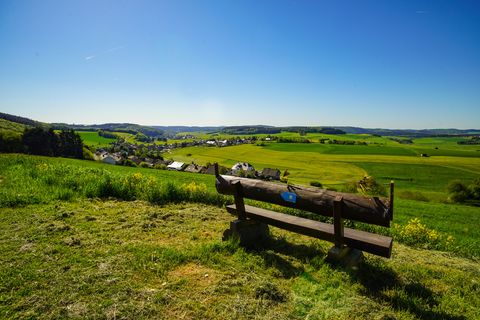 Bench on a hill with far-reaching views over fields, a village and blue sky