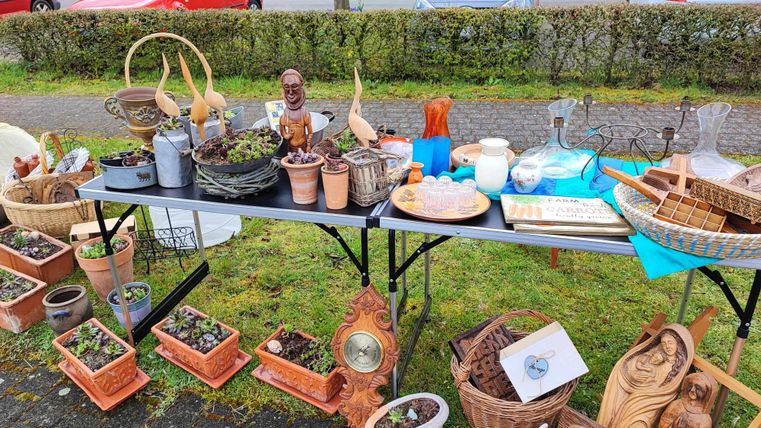 Ein Tisch mit einer Vielzahl von antiquarischen Gegenständen und Blumentöpfen. Es sind auch einige dekorative Figuren und Werkzeuge zu sehen.