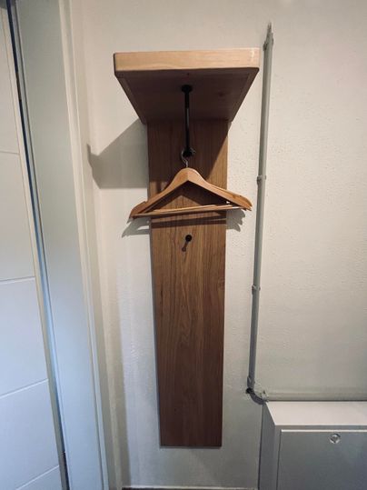 A bright wooden coat rack with a shelf above.