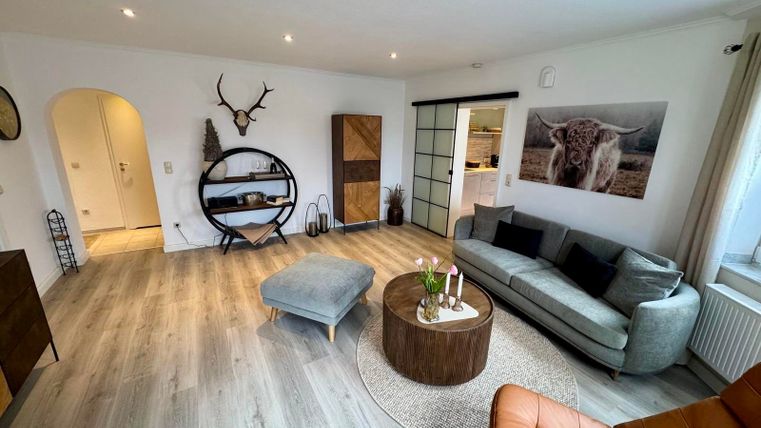 A modern, bright living room with a comfortable couch and smart TV, as well as a reading chair and direct access to the sun terrace.