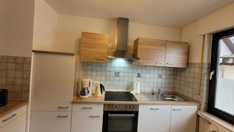 Eine moderne Küche mit hellen Schränken und einem Herd. Die Atmosphäre ist freundlich und einladend.