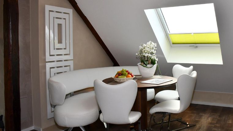 A stylish dining area with a round table and modern chairs. Large windows allow plenty of daylight and create a bright atmosphere.