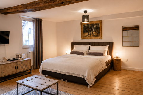 An elegant bedroom with a large bed and cozy furnishings. Wooden floor and harmonious colors create a relaxed atmosphere.