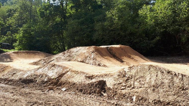 Ein Sandplatz mit Hügeln und Wellen für Radfahrer. Umgeben von dichter Vegetation und Bäumen.