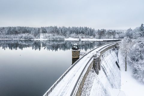 Wintery Dreilägerbach dam with snow-covered landscape and calm water.