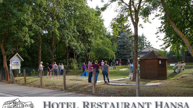 Ein belebter Minigolfplatz am Nachmittag / frühen Abend. Menschen genießen die Atmosphäre und die grüne Umgebung.