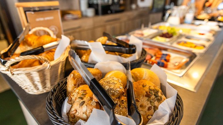 Een buffet met verse broodjes in manden. Op de achtergrond bevinden zich verschillende gerechten en snacks.