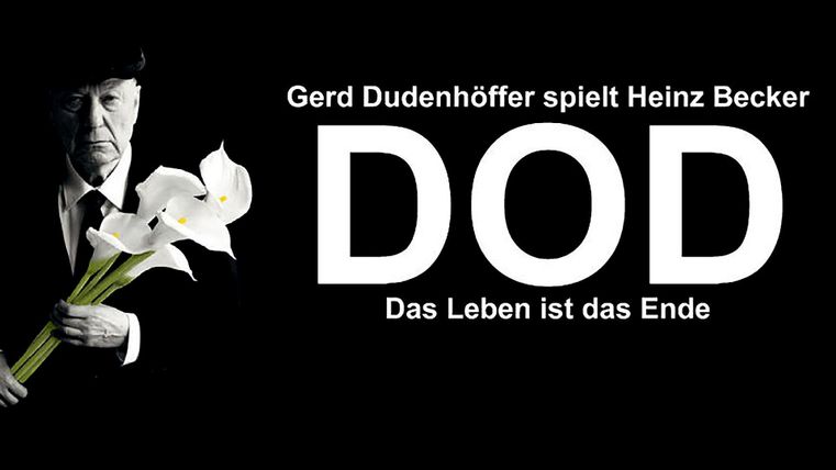 Een man in een pak houdt witte lelies vast en kijkt serieus. Op de achtergrond staat de tekst "DOD - Het leven is het einde".