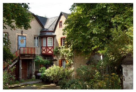 Een charmant huis met een kleurrijke gevel en een balkon. De tuin is weelderig en omgeven door bomen.