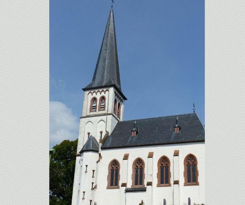 Een indrukwekkende kerk met een hoge spitse toren. De gevel is licht en heeft mooie gotische ramen.