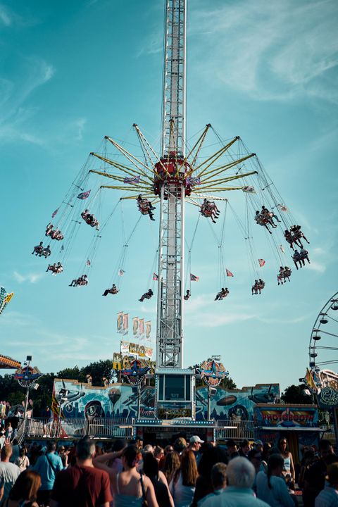 Une attraction palpitante lors d'une foire, qui soulève les balançoires dans les airs. Beaucoup de gens se tiennent à proximité et observent la scène.