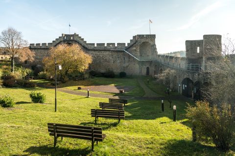 An impressive castle surrounded by green meadows and trees. Benches invite you to linger and offer a view of the historical architecture.