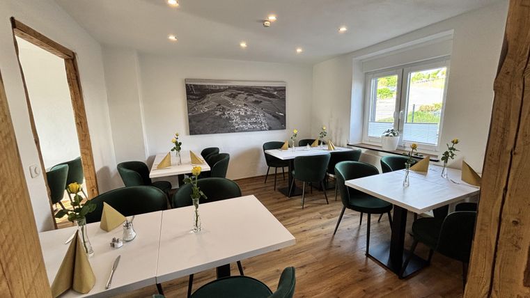 Gezellige koffiehoek met meerdere tafels van verschillende formaten en comfortabele stoelen naast een groot raam.